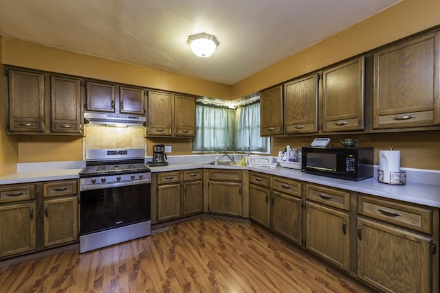10100 W Chaplin Ave, Beach Park, IL 60087 - kitchen featuring stainless steel range with gas cooktop, black microwave, under cabinet range hood, dark wood-style floors, and light countertops