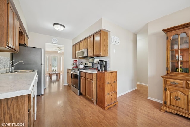 1713 Meadow Ln, Mchenry, IL 60050 - kitchen with stainless steel gas range, brown cabinets, light wood finished floors, light countertops, and decorative backsplash