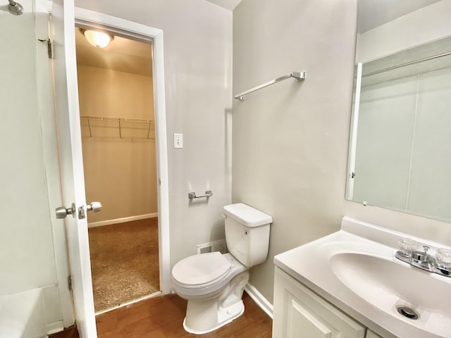 22962 Bruce Dr, Richton Park, IL 60471 - bathroom with toilet, vanity, a walk in closet, wood finished floors, and baseboards