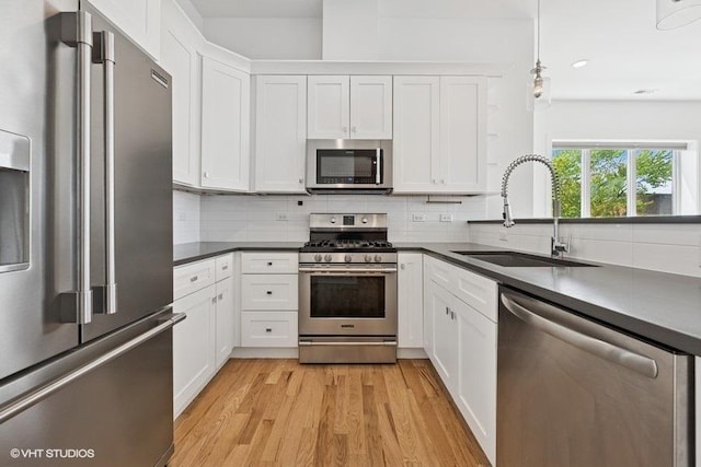 2505 W Potomac Ave Unit 3W, Chicago, IL 60622 - kitchen featuring stainless steel appliances, a sink, dark countertops, light wood finished floors, and white cabinetry