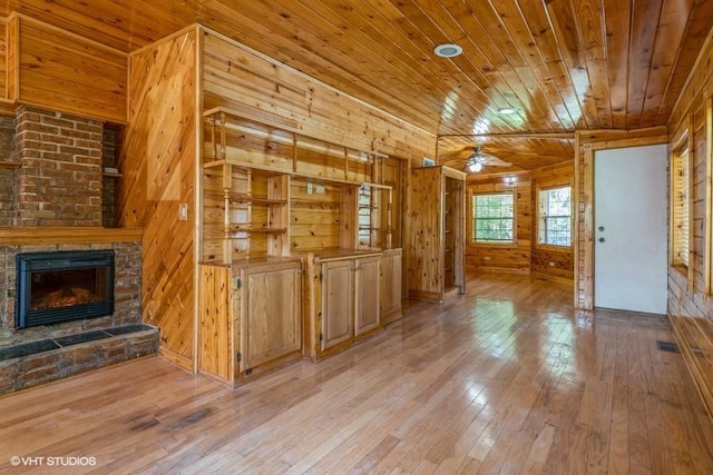 2140 Cedar Ct, Glenview, IL 60025 - unfurnished living room featuring wood walls, hardwood / wood-style floors, wood ceiling, a stone fireplace, and a ceiling fan