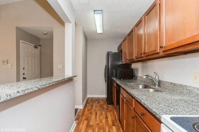 2028 N Rand Rd Unit 202, Palatine, IL 60074 - kitchen with a sink, brown cabinets, wood finished floors, a textured ceiling, and light stone countertops