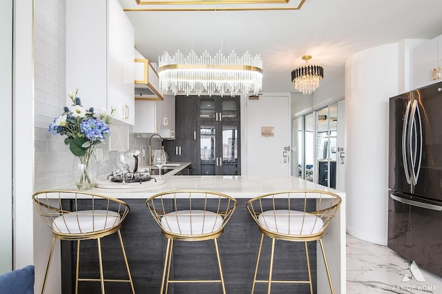 505 N Lake Shore Dr Unit 2017, Chicago, IL 60611 - kitchen featuring freestanding refrigerator, a chandelier, light marble finish floors, a peninsula, and decorative backsplash