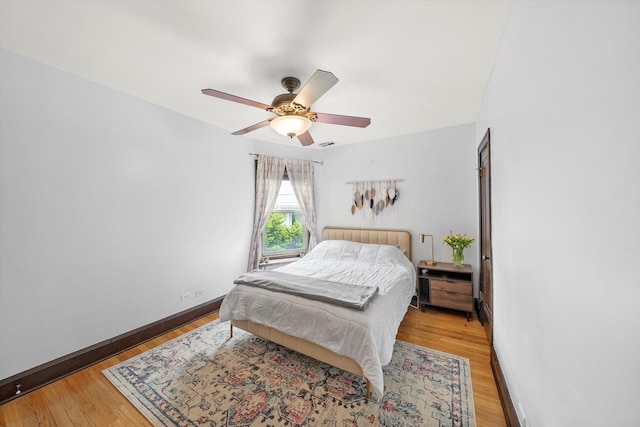 bedroom with light wood-type flooring, baseboards, and a ceiling fan