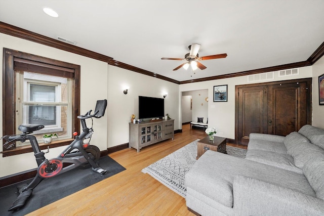 living room with ceiling fan, light wood-style floors, baseboards, and crown molding