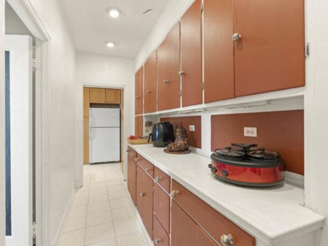 7321 S S Shore Dr Unit 11-B, Chicago, IL 60649 - kitchen featuring freestanding refrigerator, light tile patterned floors, light countertops, brown cabinets, and recessed lighting