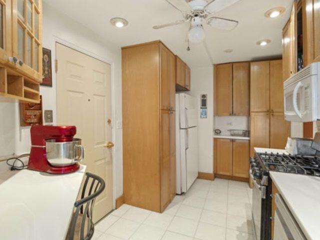 7321 S S Shore Dr Unit 11-B, Chicago, IL 60649 - kitchen featuring white appliances, ceiling fan, brown cabinets, light countertops, and glass insert cabinets