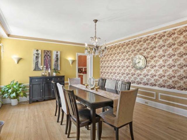 7321 S S Shore Dr Unit 11-B, Chicago, IL 60649 - dining room with a chandelier, crown molding, wainscoting, light wood finished floors, and baseboards