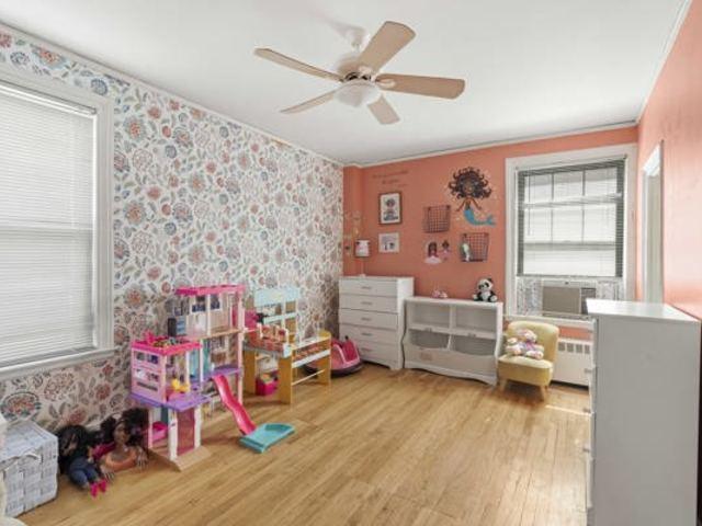 7321 S S Shore Dr Unit 11-B, Chicago, IL 60649 - game room with wood finished floors, a ceiling fan, wallpapered walls, cooling unit, and radiator