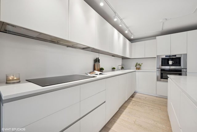 1516 N State Pkwy Unit 5D, Chicago, IL 60610 - kitchen featuring black electric cooktop, light wood-style floors, light countertops, and white cabinetry