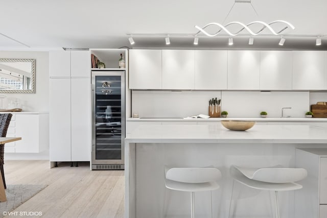 1516 N State Pkwy Unit 5D, Chicago, IL 60610 - kitchen featuring wine cooler, white cabinets, a kitchen breakfast bar, light countertops, and light wood-style flooring