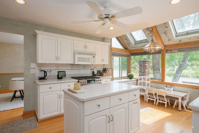 16 Lucas Dr, Palos Hills, IL 60465 - kitchen with white microwave, a skylight, stainless steel range with gas stovetop, light wood-style flooring, and recessed lighting
