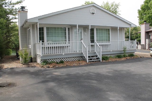 view of front facade featuring covered porch and a chimney
