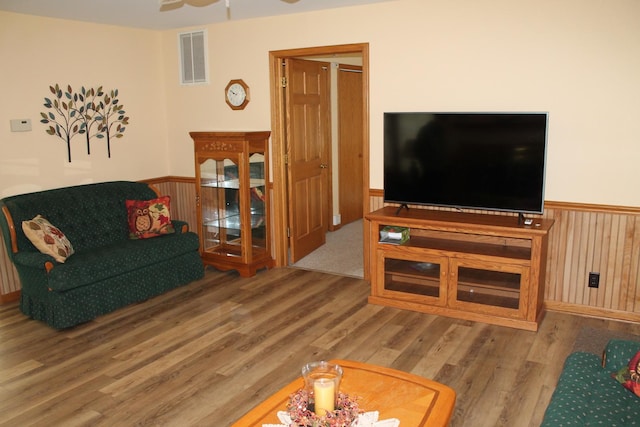 living area featuring wainscoting, wood finished floors, and ceiling fan