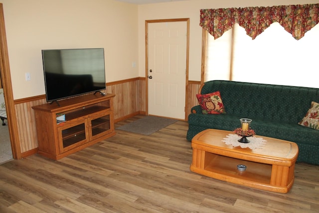 living area with wainscoting, wood finished floors, and wooden walls