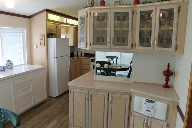 kitchen with freestanding refrigerator, dark wood-style flooring, crown molding, light countertops, and a peninsula