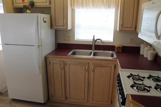 kitchen with white appliances, a sink, and dark countertops