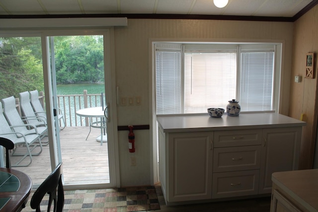 doorway featuring crown molding, wooden walls, and dark floors