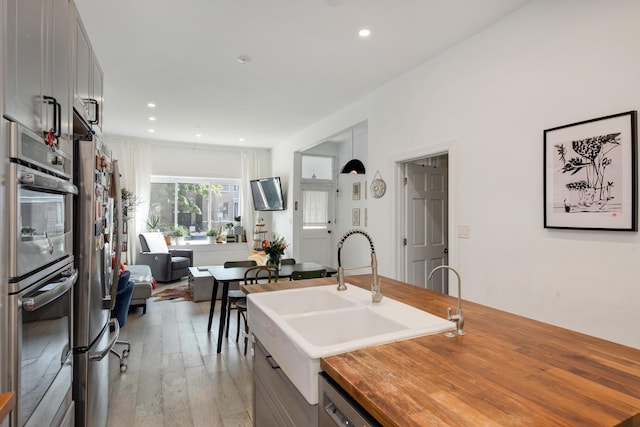 3306 W Lemoyne St, Chicago, IL 60651 - kitchen with butcher block counters, stainless steel appliances, a sink, light wood finished floors, and recessed lighting