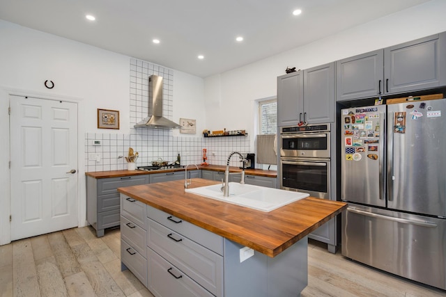 3306 W Lemoyne St, Chicago, IL 60651 - kitchen featuring butcher block countertops, stainless steel appliances, gray cabinetry, wall chimney exhaust hood, and a sink