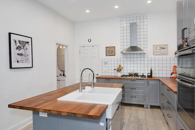3306 W Lemoyne St, Chicago, IL 60651 - kitchen featuring butcher block countertops, gray cabinets, wall chimney exhaust hood, recessed lighting, and backsplash