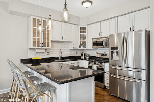 2523 N Halsted St Unit 2, Chicago, IL 60614 - kitchen featuring stainless steel appliances, a sink, dark countertops, a peninsula, and white cabinets