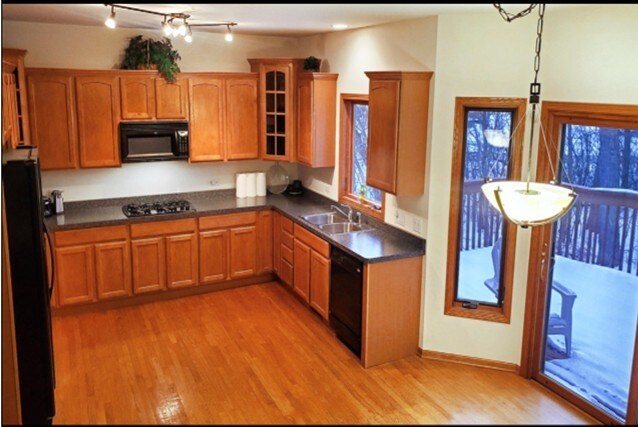 4301 Hickory Hill Ct, Johnsburg, IL 60051 - kitchen with black appliances, light wood finished floors, glass insert cabinets, and dark countertops