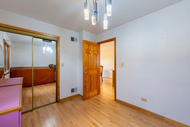 6856 W Montrose Ave, Harwood Heights, IL 60706 - unfurnished bedroom with light wood-style floors, a closet, and a chandelier