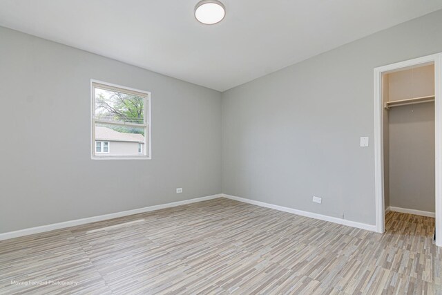12155 S Normal Ave, Chicago, IL 60628 - unfurnished bedroom with light wood-style flooring, a spacious closet, baseboards, and a closet