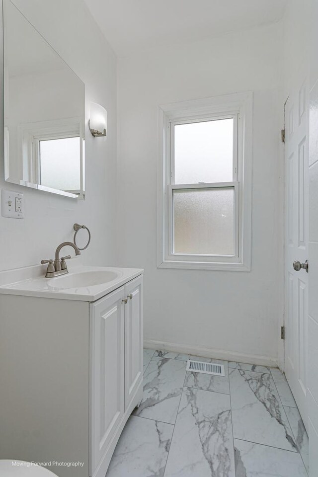 12155 S Normal Ave, Chicago, IL 60628 - bathroom with plenty of natural light, vanity, marble finish flooring, and baseboards