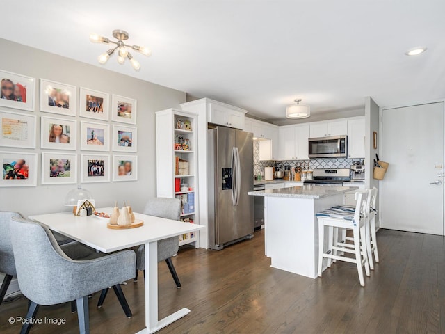 1960 N Lincoln Park W Unit 1008, Chicago, IL 60614 - kitchen featuring appliances with stainless steel finishes, a kitchen breakfast bar, white cabinets, dark wood-style flooring, and a kitchen island