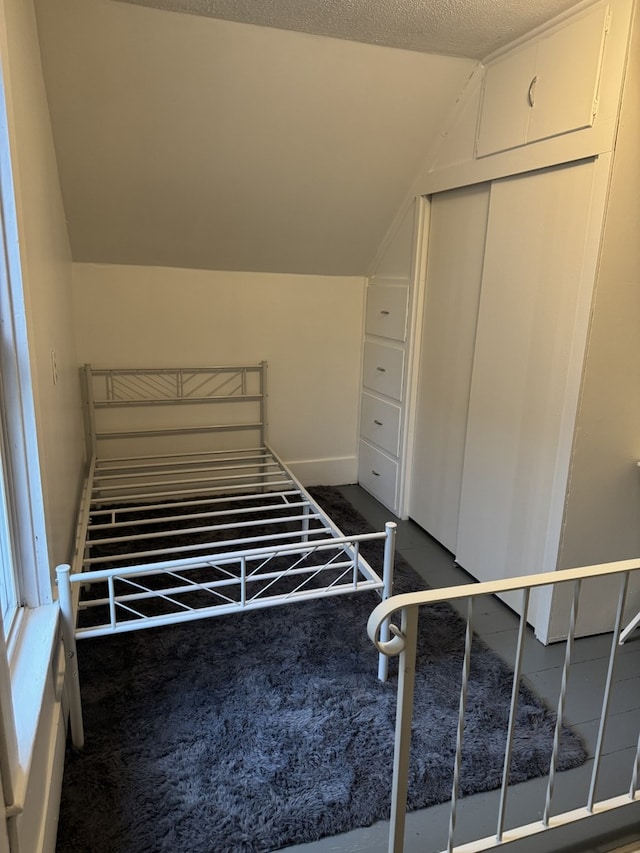 unfurnished bedroom with dark carpet and vaulted ceiling