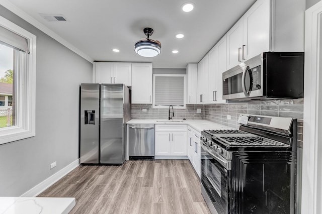 328 Nassau St, Park Forest, IL 60466 - kitchen with stainless steel appliances, a sink, decorative backsplash, white cabinets, and light wood-style flooring