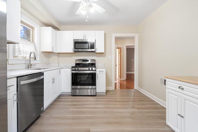 5701 N Mobile Ave, Chicago, IL 60646 - kitchen with stainless steel appliances, a sink, light countertops, a ceiling fan, and white cabinetry