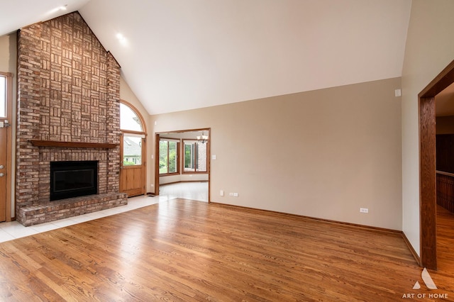 10801 Jillian Rd, Orland Park, IL 60467 - unfurnished living room with high vaulted ceiling, light wood finished floors, a brick fireplace, and baseboards