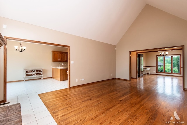 10801 Jillian Rd, Orland Park, IL 60467 - unfurnished living room with a chandelier, high vaulted ceiling, a sink, baseboards, and light wood finished floors