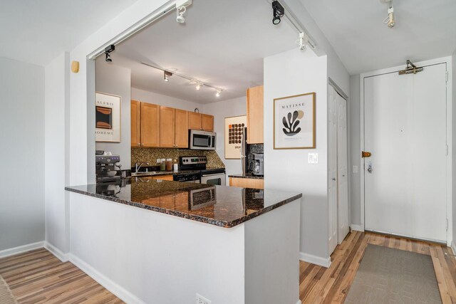 30 E Huron St Unit 4108, Chicago, IL 60611 - kitchen featuring appliances with stainless steel finishes, track lighting, light wood-style flooring, a peninsula, and dark stone counters