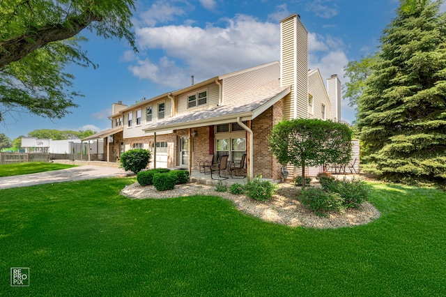9352 Sunrise Ln Unit B1, Orland Park, IL 60462 - view of front facade with a chimney, a front yard, brick siding, and a porch