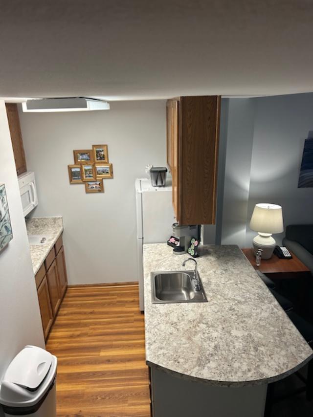 111 Center St Unit 441, Lake Geneva, WI 53147 - kitchen with a sink, wood finished floors, light countertops, and brown cabinets