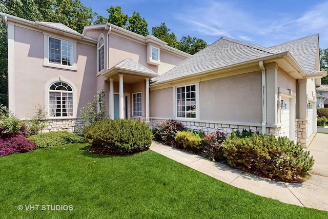 1031 S Wellington Rd, Waukegan, IL 60085 - view of front of house with stucco siding, a garage, and a front lawn
