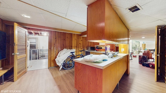 7421 N Crossway Rd, Fox Point, WI 53217 - kitchen featuring a paneled ceiling, wood finished floors, wood walls, light countertops, and stainless steel microwave