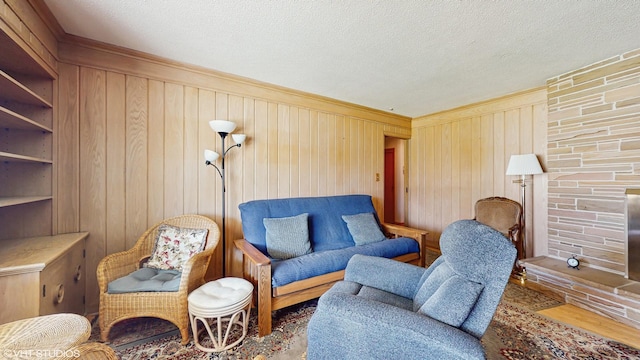 7421 N Crossway Rd, Fox Point, WI 53217 - sitting room featuring wood walls, a textured ceiling, crown molding, a fireplace, and wood finished floors