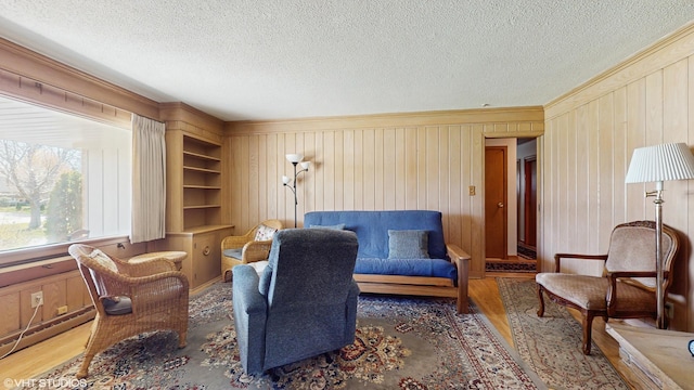 7421 N Crossway Rd, Fox Point, WI 53217 - living area featuring wood finished floors, a textured ceiling, crown molding, wood walls, and a baseboard heating unit