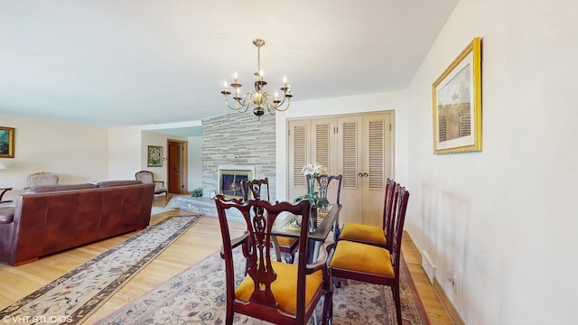 7421 N Crossway Rd, Fox Point, WI 53217 - dining room with light wood-style floors, a chandelier, baseboards, and a large fireplace