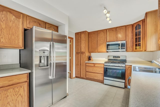 1328 Sunrise Ln, Gurnee, IL 60031 - kitchen with appliances with stainless steel finishes, a sink, glass insert cabinets, and decorative backsplash
