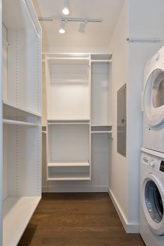 200 E Delaware Pl Unit 18F, Chicago, IL 60611 - laundry room featuring stacked washer / drying machine, track lighting, dark wood-type flooring, baseboards, and electric panel