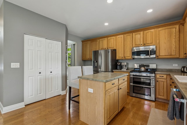 727 Sumac Dr, Aurora, IL 60506 - kitchen with appliances with stainless steel finishes, light wood-style floors, a kitchen island, recessed lighting, and a sink
