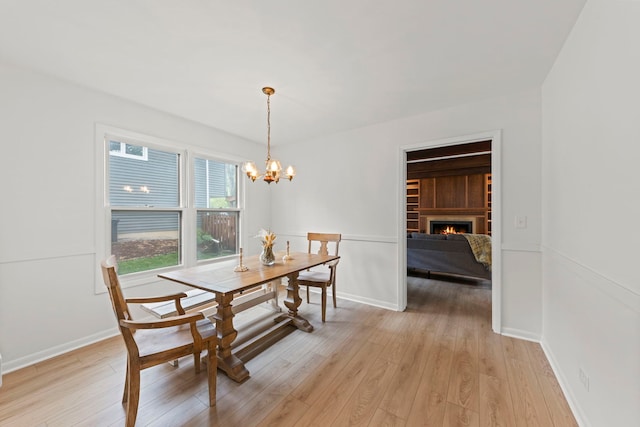 2S644 Devonshire Ln, Glen Ellyn, IL 60137 - dining space featuring light wood finished floors, a chandelier, a lit fireplace, and baseboards