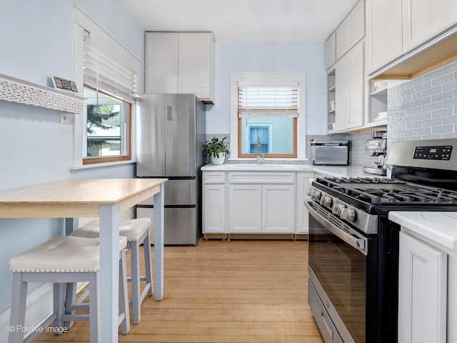 11 S Catherine Ave, La Grange, IL 60525 - kitchen with appliances with stainless steel finishes, a sink, light wood-style floors, white cabinets, and backsplash