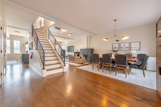 2044 W Roscoe St Unit 2S, Chicago, IL 60618 - dining room with stairway, wood finished floors, a chandelier, a fireplace, and baseboards